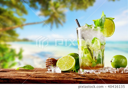 Fresh mojito drink placed on wooden planks, blur beach on background Fresh mojito drink placed on wooden planks, blur beach on background 40416135