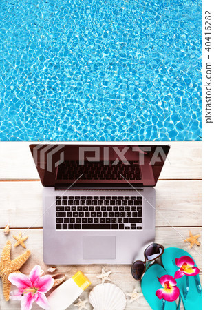 Laptop with beach accessories on wood deck 40416282