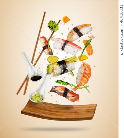Flying sushi pieces served on wooden plate, separated on colored background 40416333