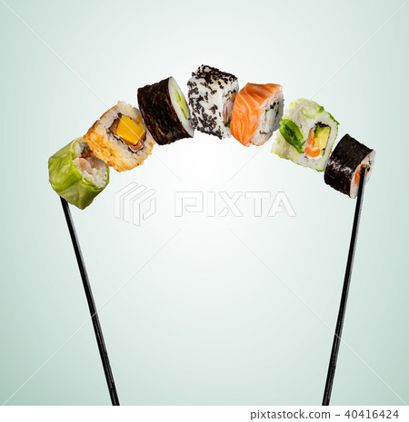 Sushi pieces placed between chopsticks on soft background Sushi pieces placed between chopsticks on soft background 40416424