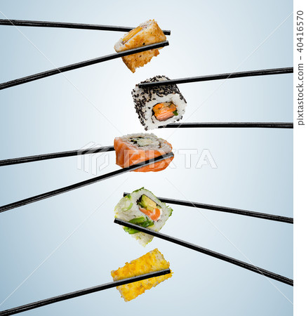 Sushi pieces placed between chopsticks, on soft background 40416570