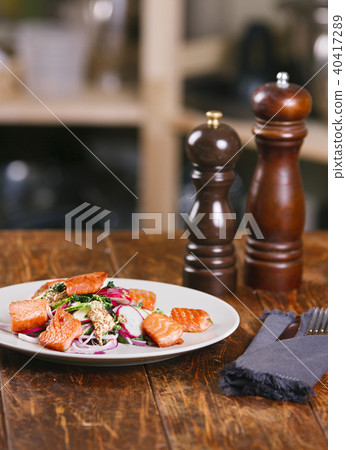 Grilled salmon with radish and spinach, served on white plate. View from above, top studio shot 40417289