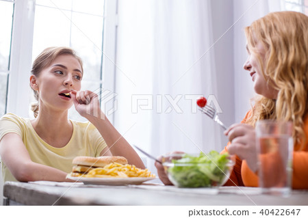 Serious slim woman having lunch with her friend Serious slim woman having lunch with her friend 40422647