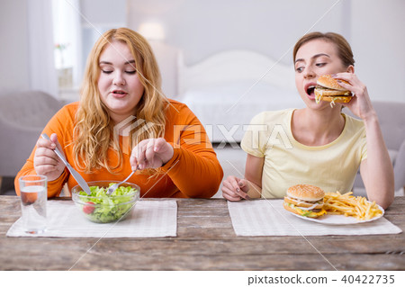 Concentrated slim woman having lunch with her friend 40422735