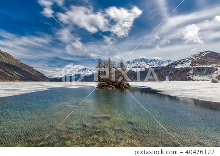 Thaw in Lake of the Swiss Alps. Small islet 40426122