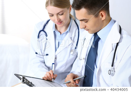 Doctors writing papers using clipboard. Physicians discussing medication program or studying at 40434005