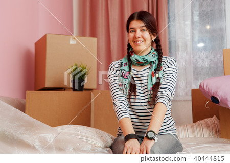Photo of happy woman sitting on sofa among cardboard boxes 40444815
