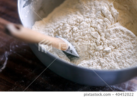 Flour in a bowl with a spatula on a dark wooden 40452022