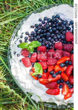 Pavlova with berries and fruit stands on the grass Pavlova with berries and fruit stands on the grass 40452136
