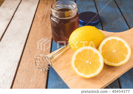 A glass of honey with dipper and lemon on a table. A glass of honey with dipper and lemon on a table. 40454377
