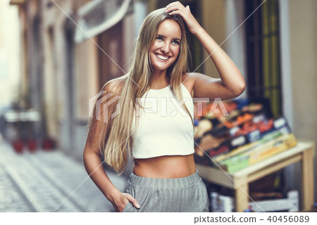 Beautiful young blonde woman smiling in urban background. 40456089
