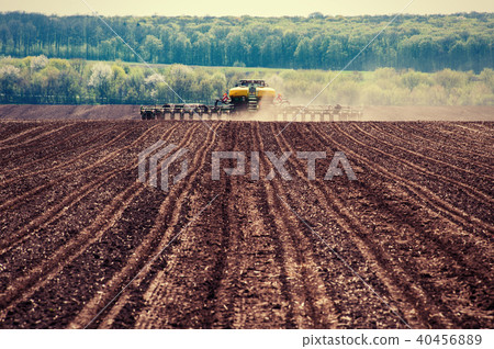 Tractor plowing farm field in preparation for spring planting 40456889