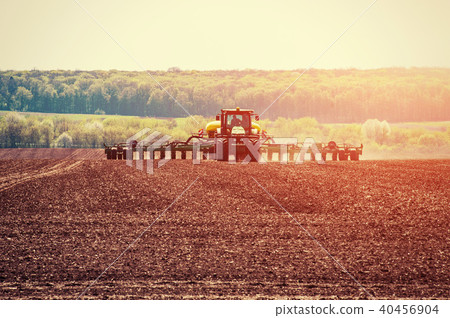 Tractor plowing farm field in preparation for spring planting 40456904