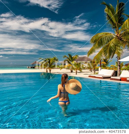 Woman with hat at beach pool in Maldives Woman with hat at beach pool in Maldives 40473578