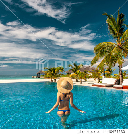 Woman with hat at beach pool in Maldives Woman with hat at beach pool in Maldives 40473580