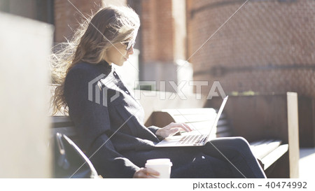 Serious girl in glasses, coffee, notebook, bench 40474992