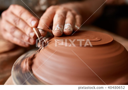 Close-up hands of a male potter in apron making a vase from clay, selective focus Close-up hands of a male potter in apron making a vase from clay, selective focus 40480652