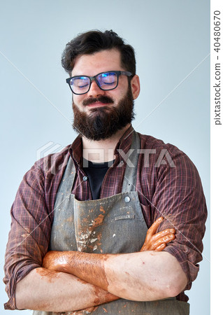 Portrait of a male potter in apron molds bowl from clay, selective focus, close-up 40480670