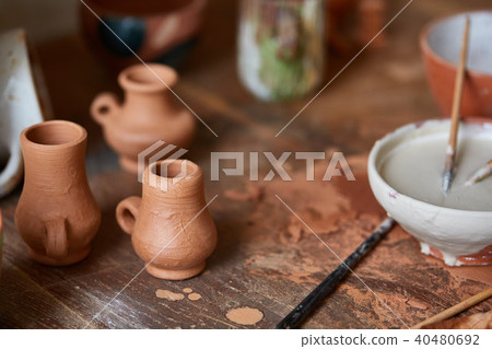 Close-up of various paint mugs and brushes in holder on worktop, selective focus, side view. Close-up of various paint mugs and brushes in holder on worktop, selective focus, side view. 40480692