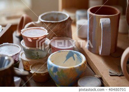 Close-up of various paint mugs and brushes in holder on worktop, selective focus, side view. Close-up of various paint mugs and brushes in holder on worktop, selective focus, side view. 40480701