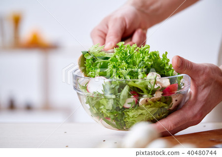 Man cooking at kitchen making healthy vegetable salad, close-up, selective focus. 40480744