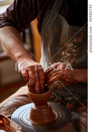 Portrait of a male potter in apron molds bowl from clay, selective focus, close-up 40480745
