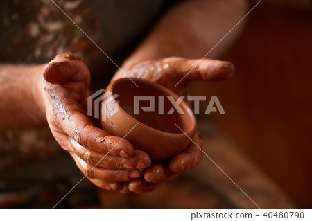 Close-up hands of a male potter in apron making a vase from clay, selective focus 40480790