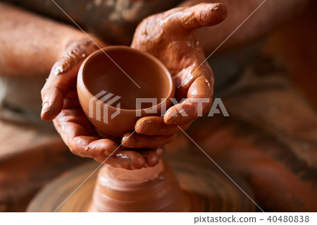 Close-up hands of a male potter in apron making a vase from clay, selective focus 40480838