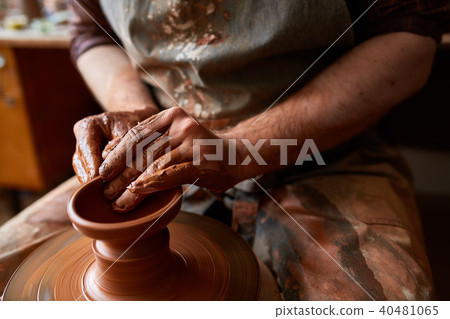 Close-up hands of a male potter in apron making a vase from clay, selective focus 40481065