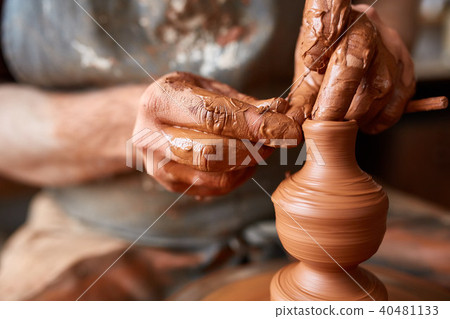 Close-up hands of a male potter in apron making a vase from clay, selective focus 40481133