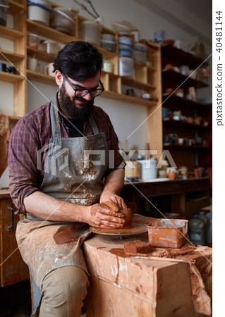 Portrait of a male potter in apron molds bowl from clay, selective focus, close-up Portrait of a male potter in apron molds bowl from clay, selective focus, close-up 40481144