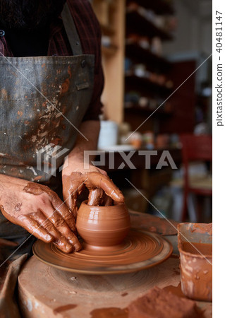 Portrait of a male potter in apron molds bowl from clay, selective focus, close-up 40481147