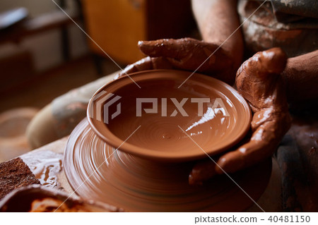 Close-up hands of a male potter in apron making a vase from clay, selective focus Close-up hands of a male potter in apron making a vase from clay, selective focus 40481150
