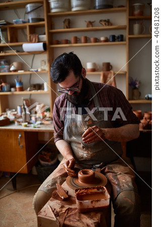 Portrait of a male potter in apron molds bowl from clay, selective focus, close-up 40481208