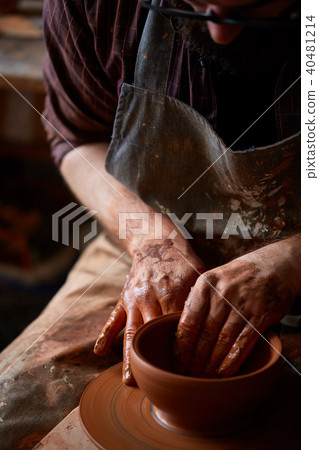 Portrait of a male potter in apron molds bowl from clay, selective focus, close-up 40481214