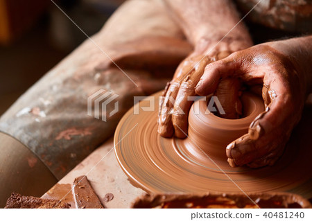 Close-up hands of a male potter in apron making a vase from clay, selective focus 40481240