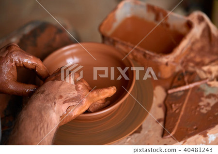 Close-up hands of a male potter in apron making a vase from clay, selective focus Close-up hands of a male potter in apron making a vase from clay, selective focus 40481243