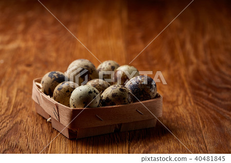 Quail eggs in a box on a rustic wooden background, top view, selective focus. Quail eggs in a box on a rustic wooden background, top view, selective focus. 40481845