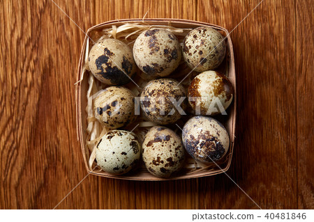 Quail eggs in a box on a rustic wooden background, top view, selective focus. Quail eggs in a box on a rustic wooden background, top view, selective focus. 40481846