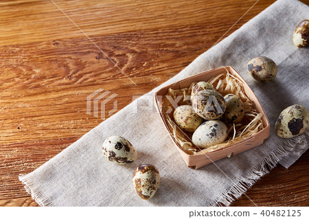 Quail eggs in the container over rustic wooden table, close-up, high angle view, selective focus. 40482125