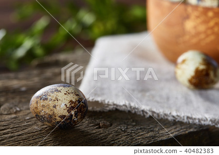 Bowl with eggs quail, eggs on a homespun napkin, boxwood on wooden background, close-up, selective 40482383