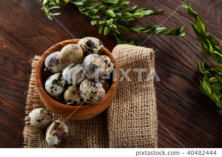 Bowl with eggs quail, eggs on a homespun napkin, boxwood on wooden background, close-up, selective Bowl with eggs quail, eggs on a homespun napkin, boxwood on wooden background, close-up, selective 40482444