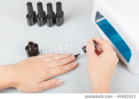 nail care. a woman covers her nails with transparent lacquer. 40482613