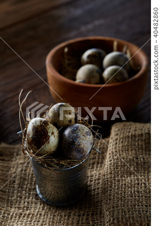 Rustic still life with quail eggs in bucket, box and bowl on a linen napkin over wooden background 40482860