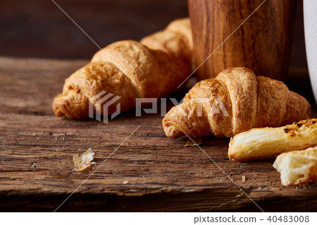 Puff pastries on piece of board over dark wooden table, close-up, selective focus, backlight. 40483008