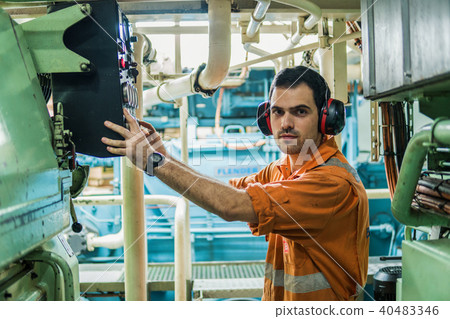 Marine engineer inspecting ship's engine in engine control room 40483346