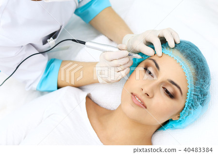 Professional beautician doing eyebrow tattoo at woman face. Permanent brow makeup in beauty salon 40483384