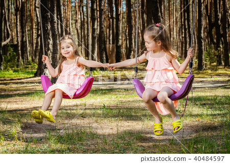 small girls on swings are holding hands small girls on swings are holding hands 40484597
