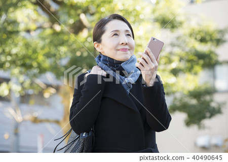 Outdoor mature woman and smartphone Outdoor mature woman and smartphone 40490645