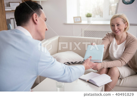 Cheerful senior psychologist recommending book 40491829